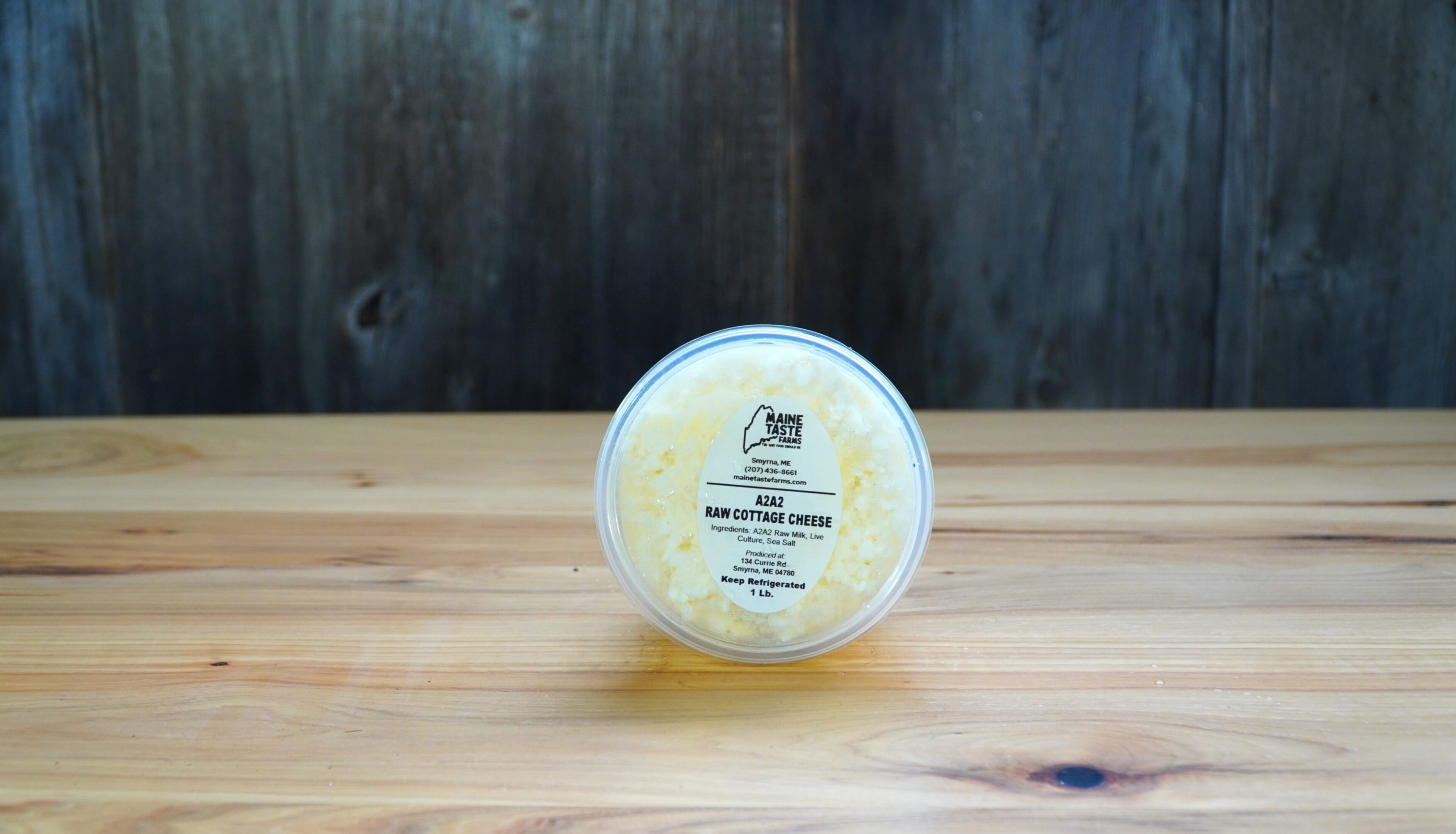 A container of cheese on top of a wooden table.