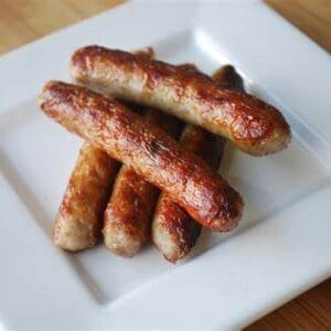 Grilled sausages on a white square plate.