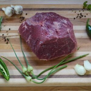 A raw steak on top of a wooden cutting board.