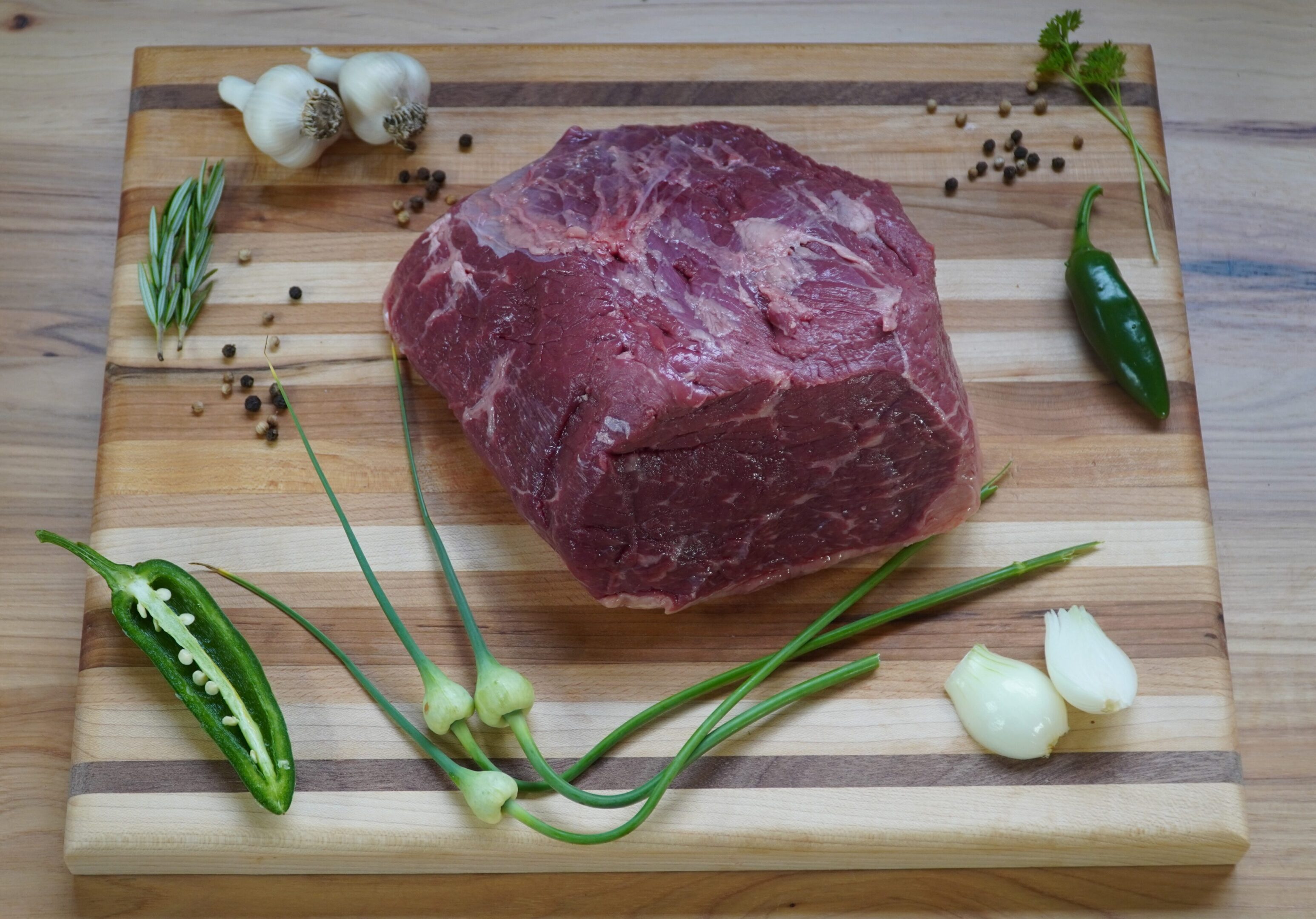 A raw steak on top of a wooden cutting board.