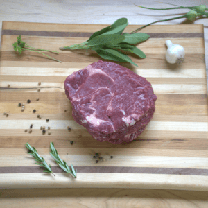A raw steak on top of a wooden cutting board.