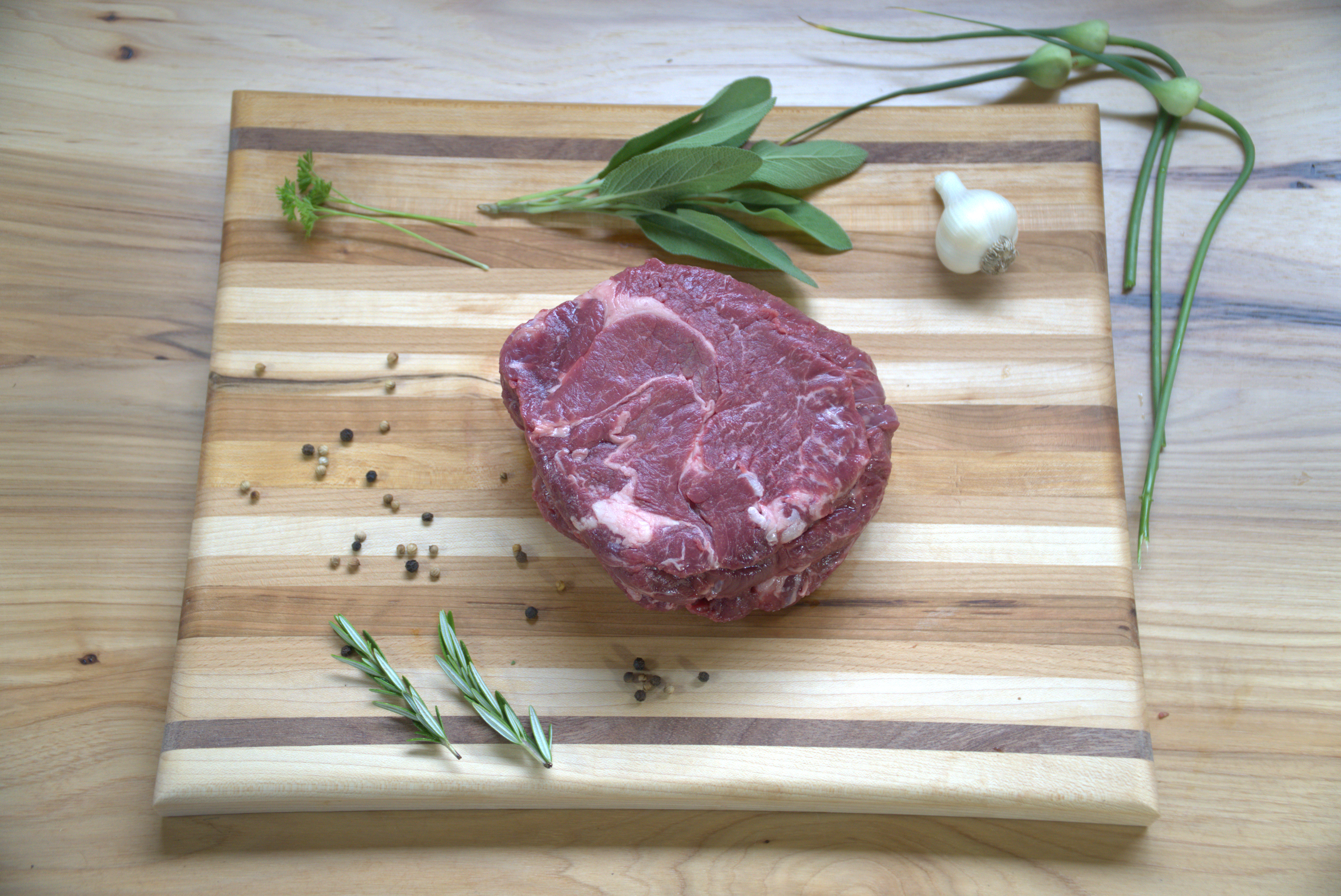 A raw steak on top of a wooden cutting board.
