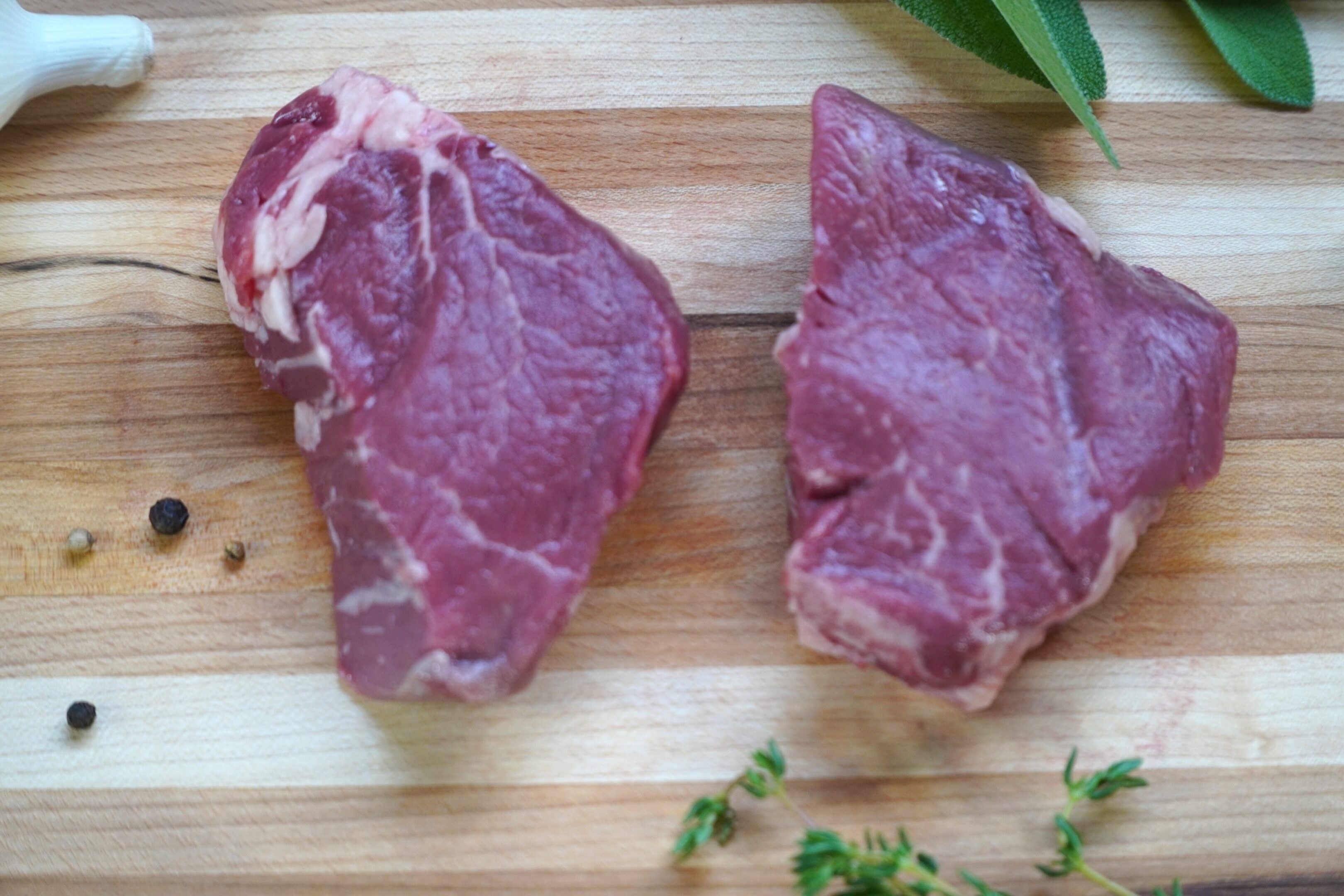 A piece of meat on top of a wooden cutting board.