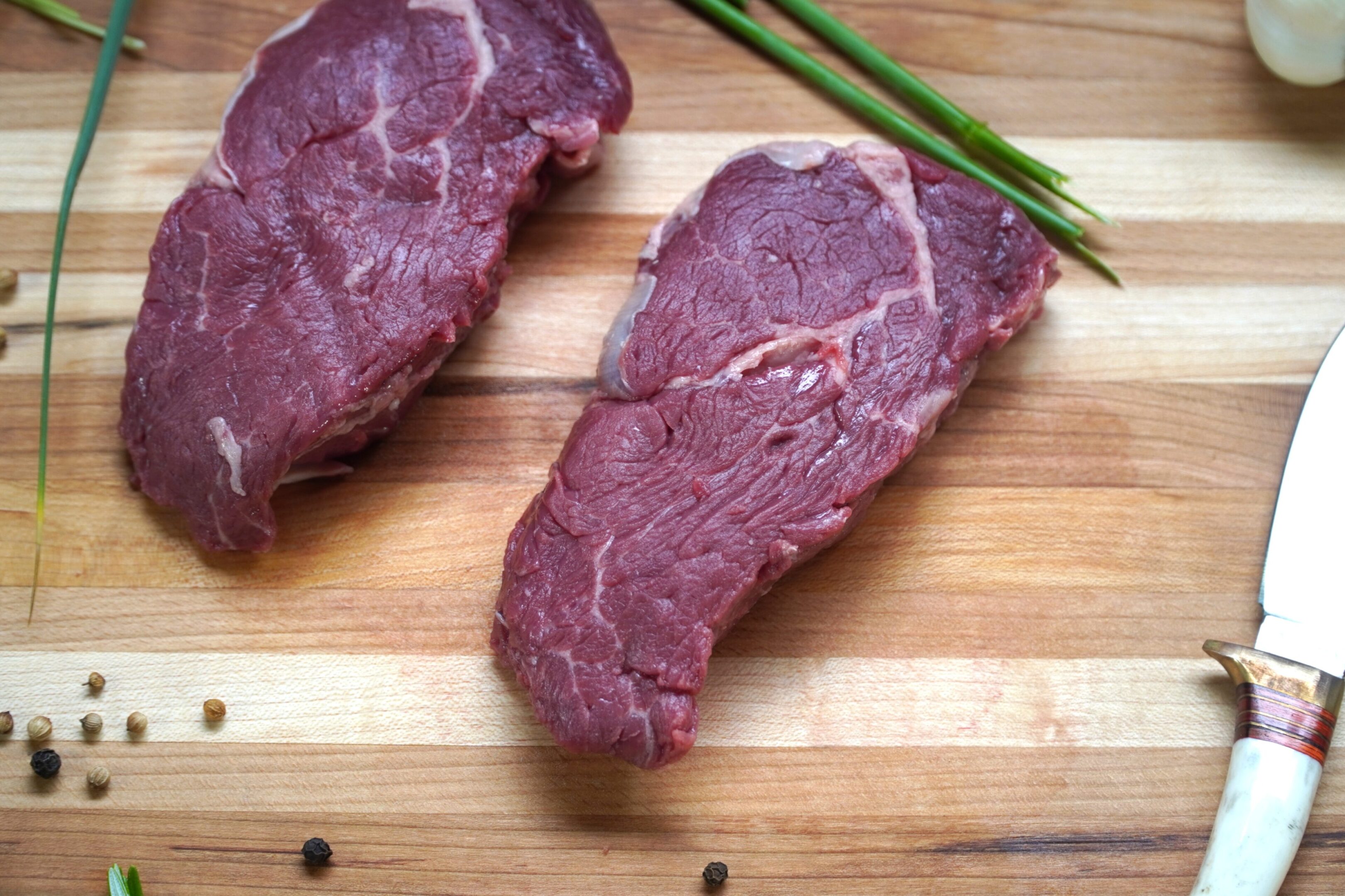A piece of meat on top of a wooden cutting board.
