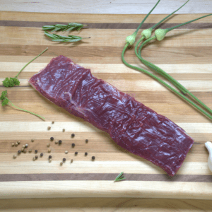 A piece of meat on top of a wooden cutting board.