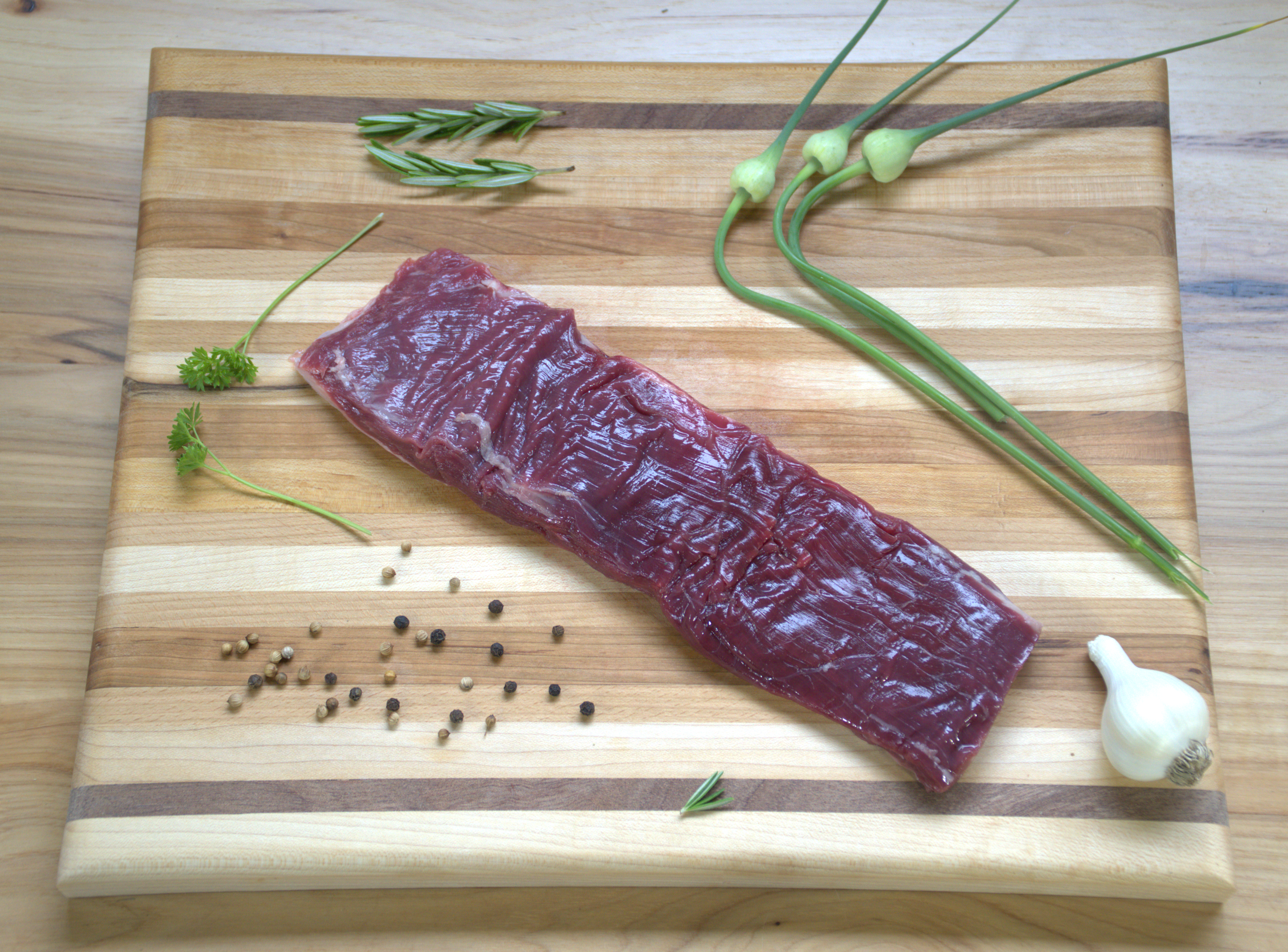 A piece of meat on top of a wooden cutting board.