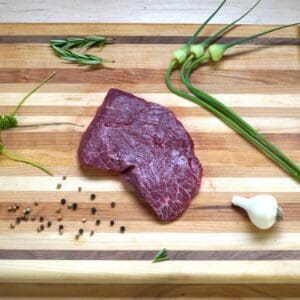 A piece of meat on top of a wooden cutting board.