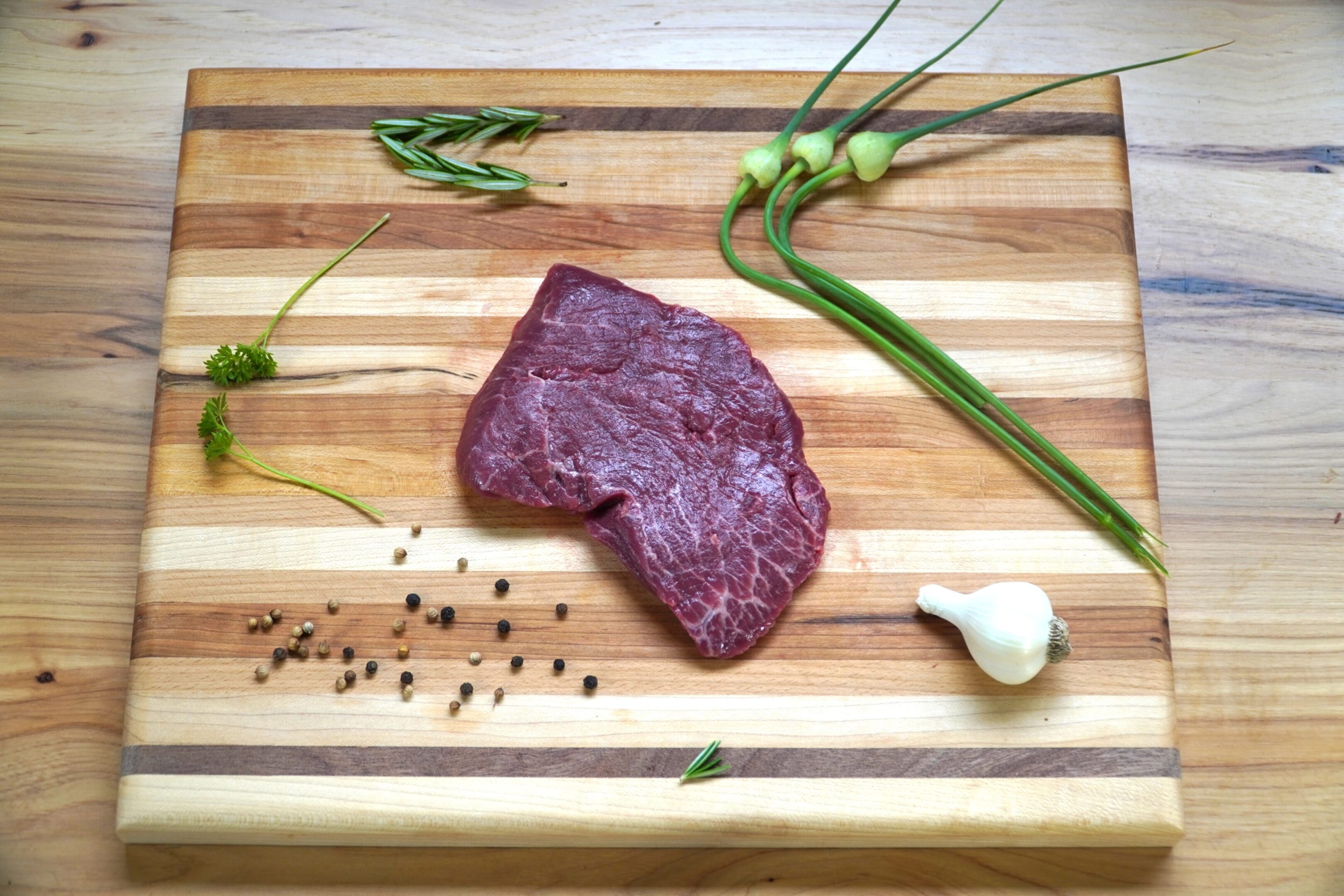 A piece of meat on top of a wooden cutting board.