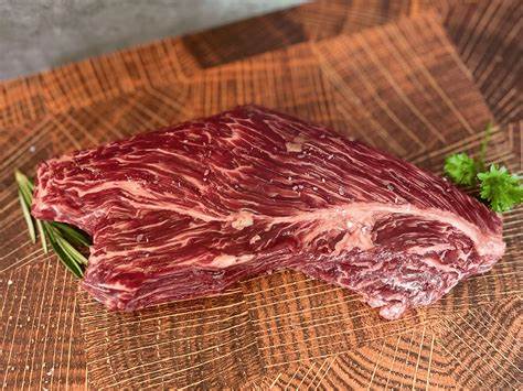 A piece of meat on top of a wooden cutting board.