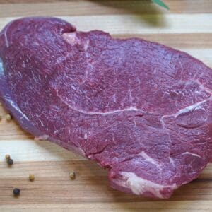 A piece of meat on top of a wooden cutting board.