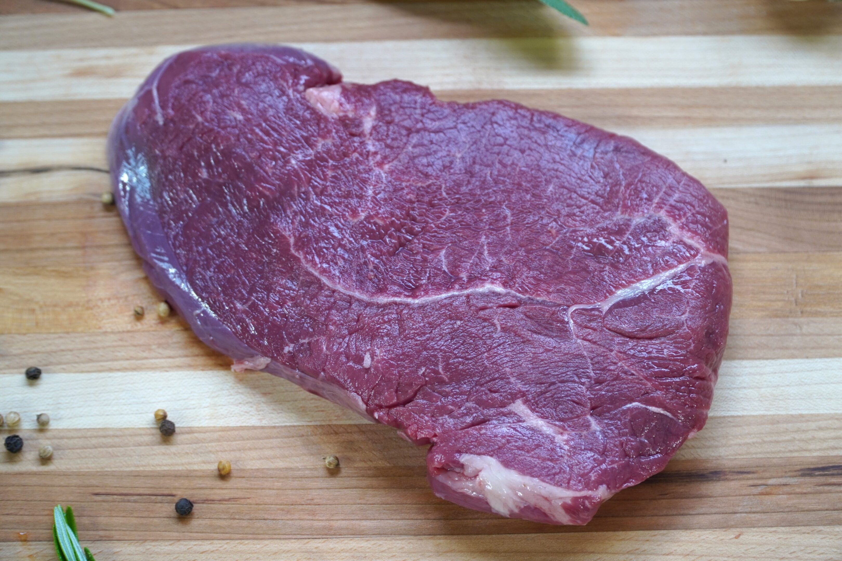 A piece of meat on top of a wooden cutting board.