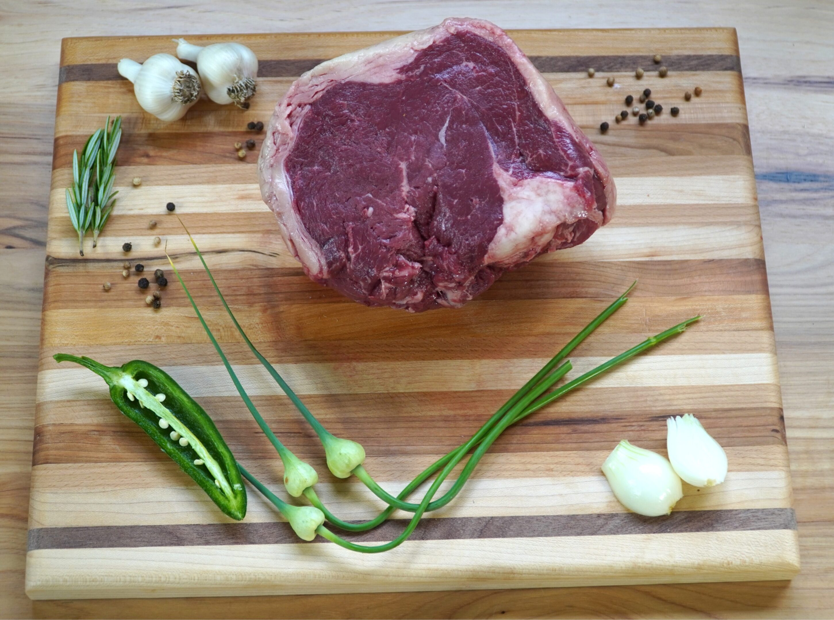 A raw steak on top of a wooden cutting board.