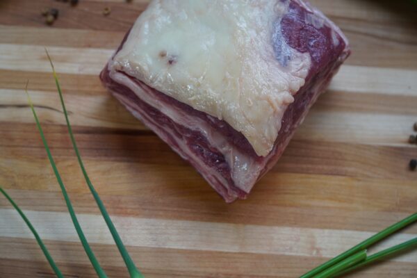 A piece of meat on top of a wooden cutting board.