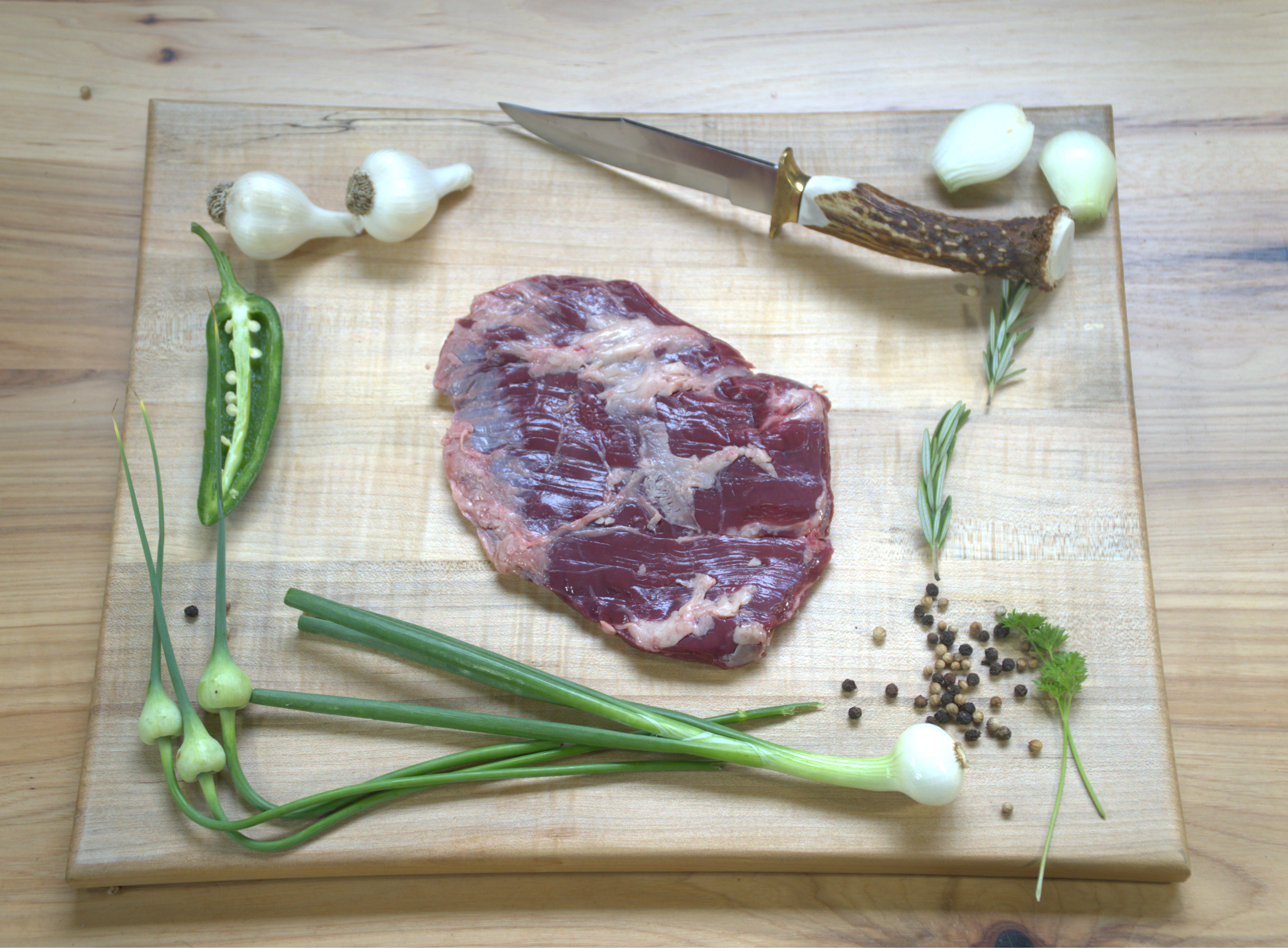 A piece of meat and vegetables on a cutting board.