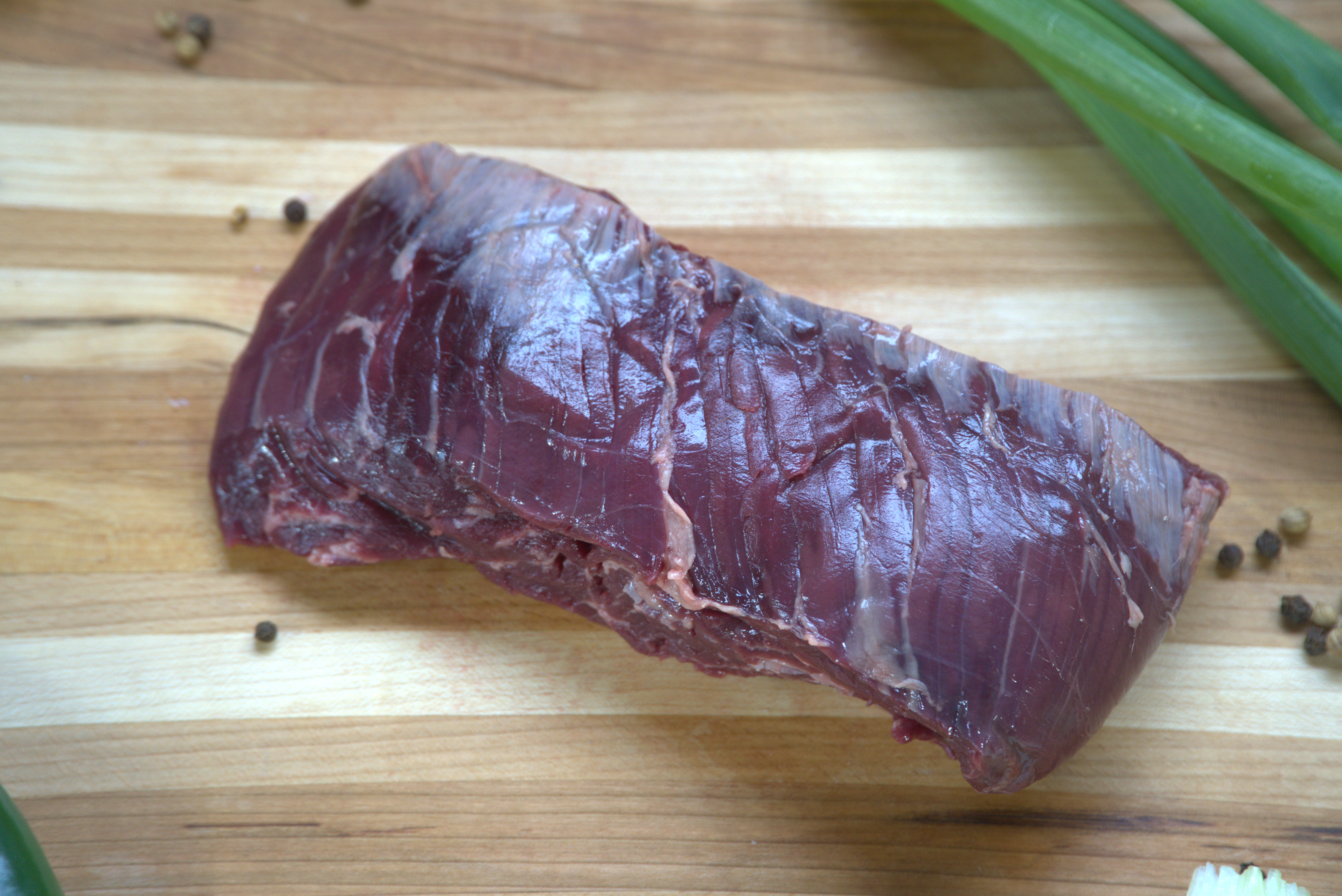 A piece of meat on top of a wooden cutting board.