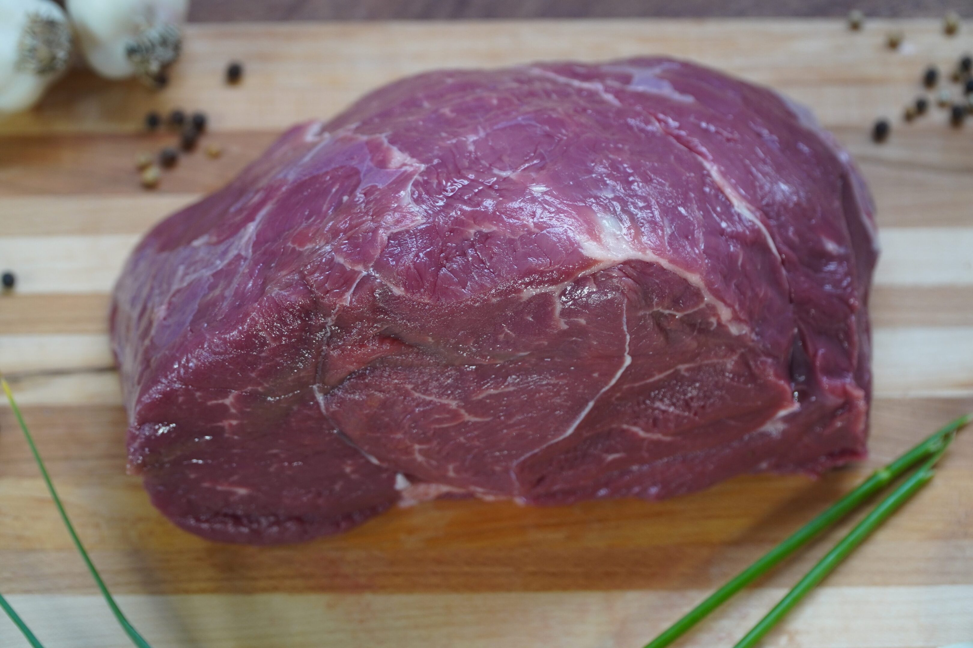 A piece of meat on top of a wooden cutting board.