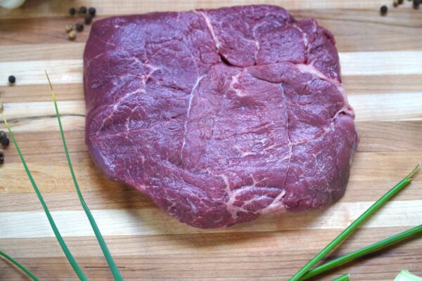 A piece of meat sitting on top of a wooden cutting board.