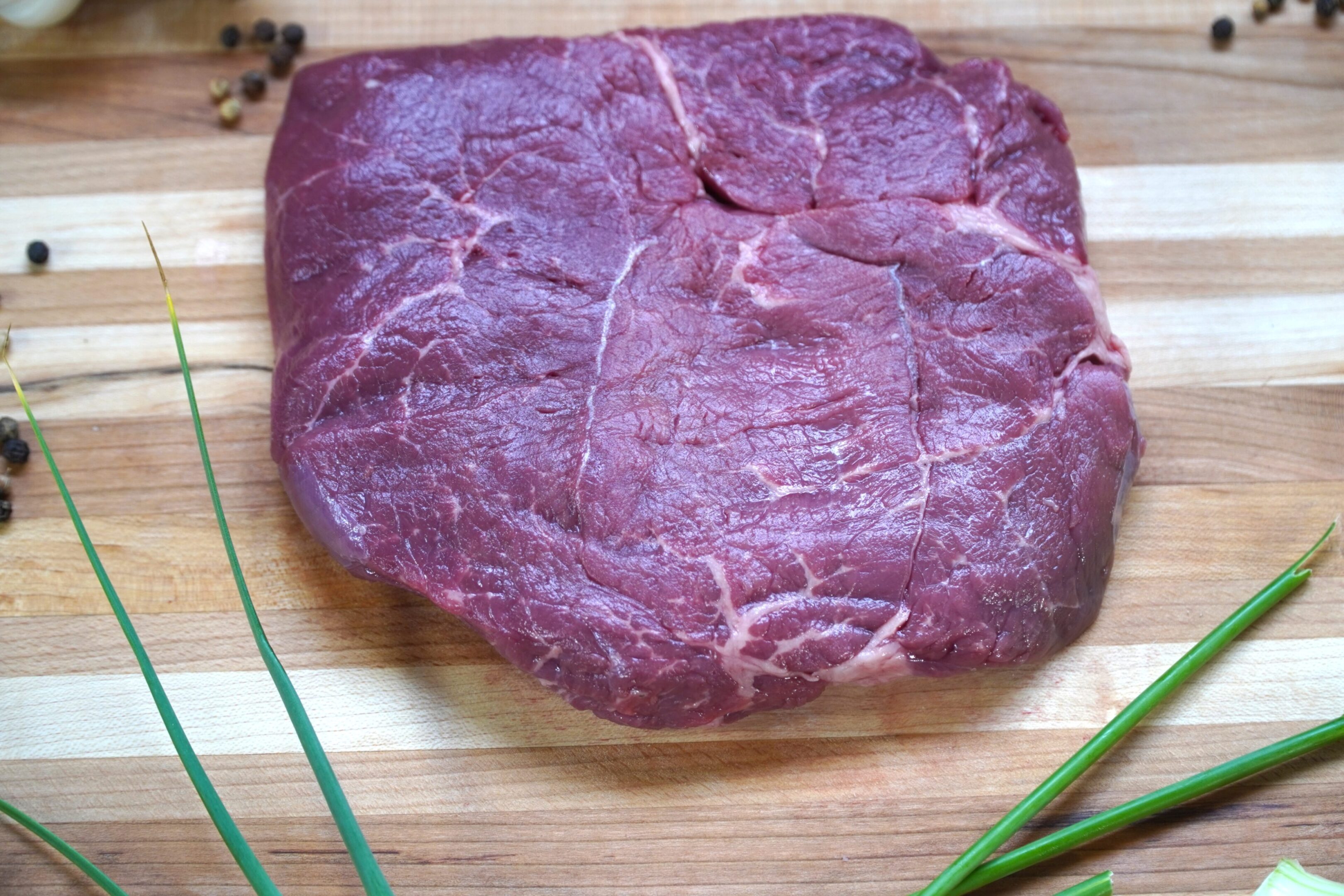 A piece of meat sitting on top of a wooden cutting board.