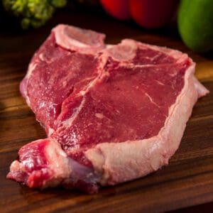 A piece of raw meat on top of a wooden cutting board.