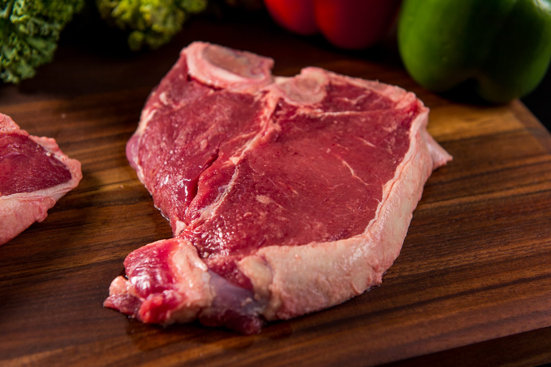 A piece of raw meat on top of a wooden cutting board.