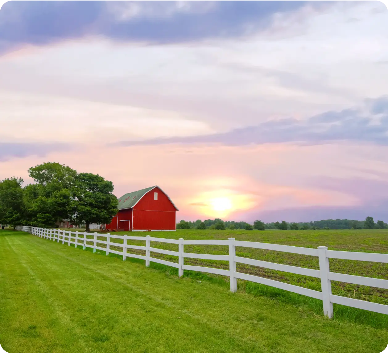 A red barn sitting next to a white fence.