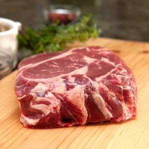 A piece of raw meat on top of a wooden cutting board.