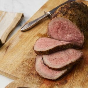 Roast beef slices on wooden cutting board.