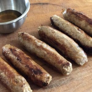 Sausages with sauce on wooden board.