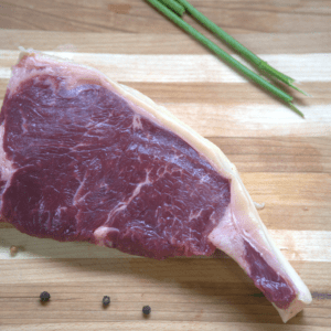 A piece of meat on top of a wooden cutting board.