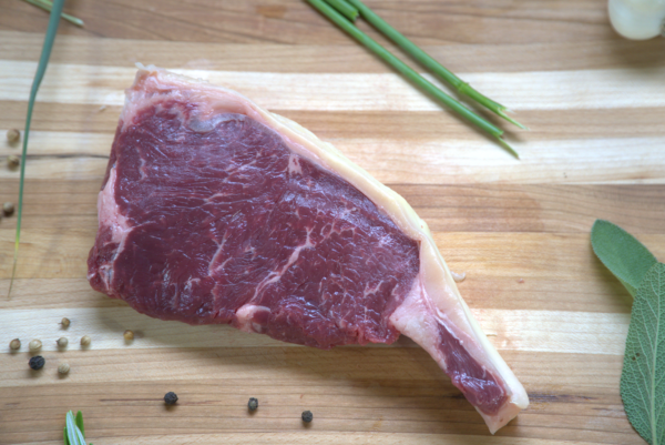 A piece of meat on top of a wooden cutting board.