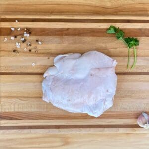 A wooden cutting board with meat and garlic on it.