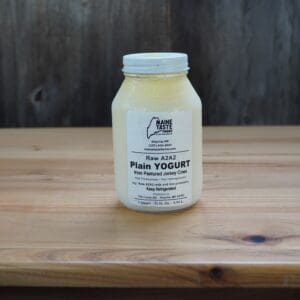 A jar of yogurt on top of a wooden table.