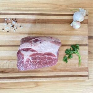 A raw meat on a cutting board with garlic and parsley.