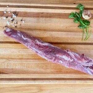 A piece of meat on top of a wooden cutting board.