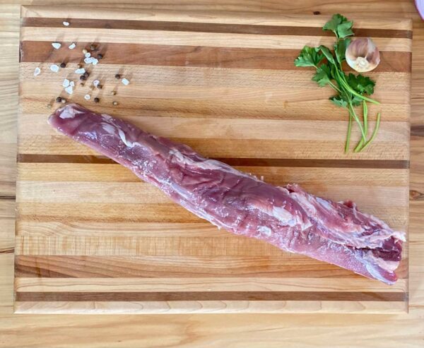A piece of meat on top of a wooden cutting board.
