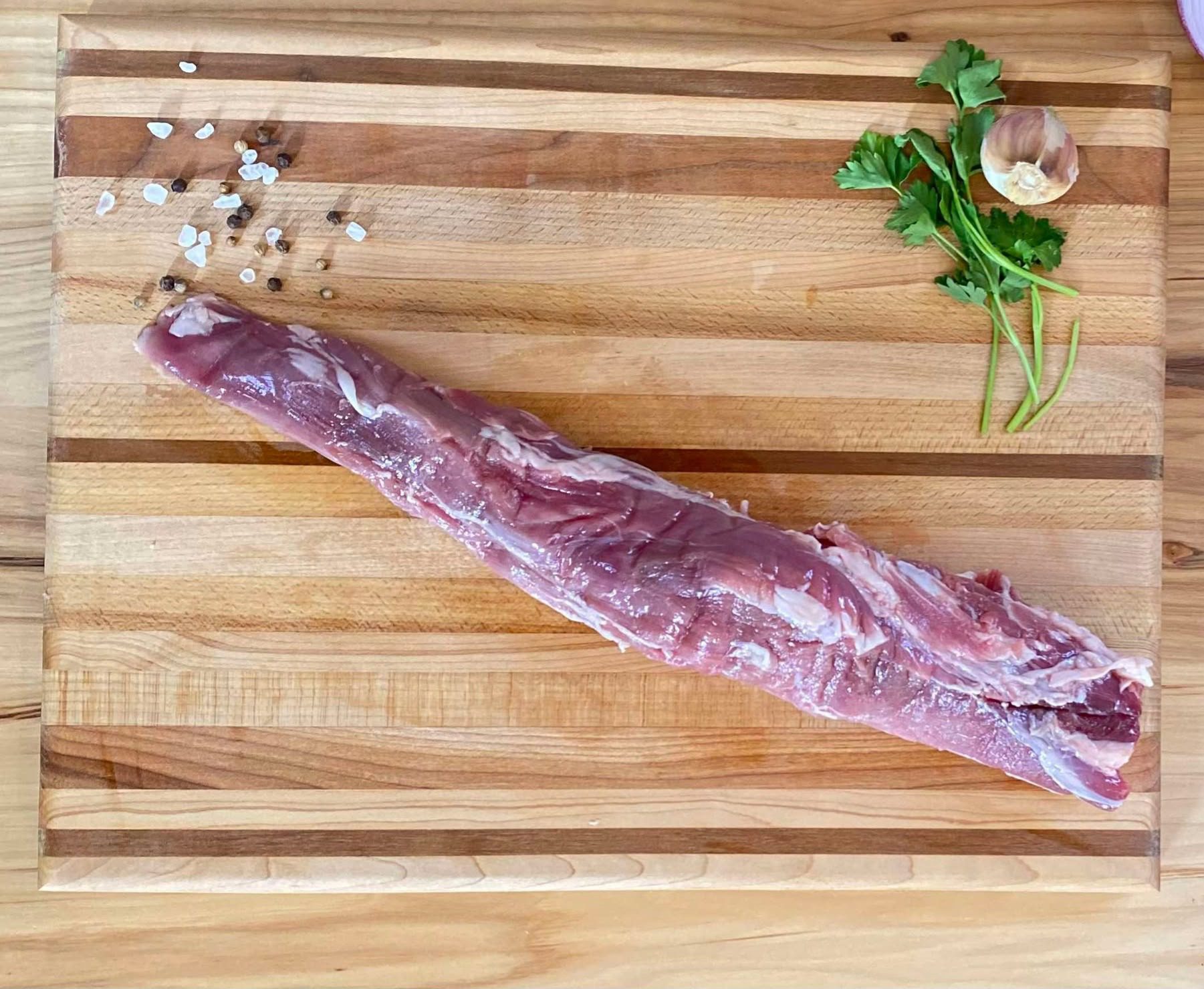 A piece of meat on top of a wooden cutting board.