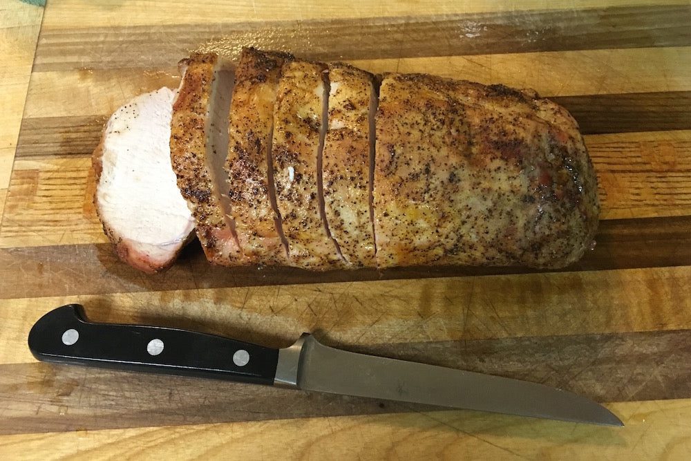 A knife and some meat on a cutting board