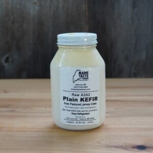 A jar of plain kefir on top of a wooden table.