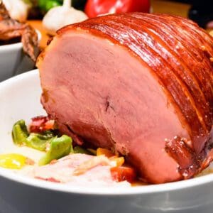 Roast ham with vegetables on plate.