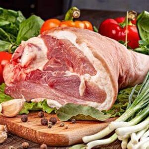 Raw meat with vegetables on wooden board.