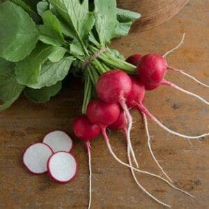 Fresh radishes with leaves on wooden surface.